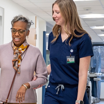 senior female patient and nurse walking in hospital hallway